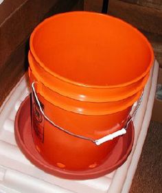 three orange buckets sitting on top of a white stand