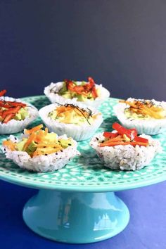 there are many sushi cups on the blue platter with rice and carrots