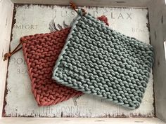 two crocheted dishcloths sitting on top of a wooden box