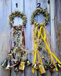 two bells hanging from the side of a wooden wall with ribbons and bows around them