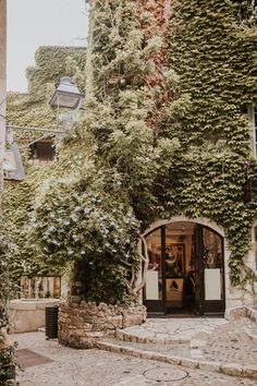 an old building with ivy growing on it's side and people standing in the doorway