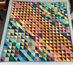 a multicolored quilt is displayed on a table