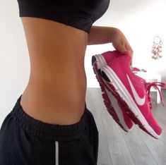 a woman is showing off her pink nike shoe and black shorts while standing on the floor