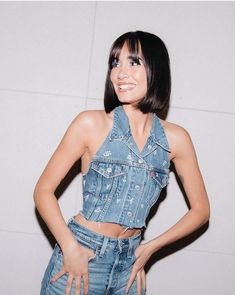 a woman with her hands on her hips posing for the camera, wearing denim overalls