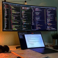 an open laptop computer sitting on top of a desk next to a large monitor screen