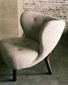 a white chair sitting on top of a carpeted floor next to a brick wall