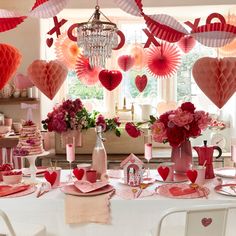 valentine's day table setting with pink and red paper hearts hanging from the ceiling