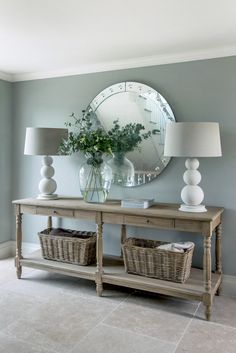 a table with two lamps and a mirror on the wall above it, in a living room