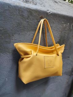 Corvo leather purse in yellow. A beautiful leather shoulder bag that can also be used as a crossbody, perfect for everyday use. It complements any outfit, from casual to formal, making it ideal for business meetings and special occasions. This bag will become your go-to accessory for every look! This handmade purse, crafted by local artisans in our studio, is made from genuine Italian cow leather and features a soft cotton lining with leather details. Inside, there's a small leather pocket, and it closes with a magnetic snap for convenience. The bag includes two straps: a short leather strap and a long adjustable strap made from a combination of leather and fabric. All hardware parts are in silver. Dimensions: Length 33 cm (13 in), Height 20 cm (7,9 in), Depth 10 cm (3,95 in). We ship all Luxury Shoulder Bag With Leather Handles For Everyday, Yellow Satchel Shoulder Bag, Elegant Yellow Shoulder Bag For Daily Use, Yellow Pouch Bag With Detachable Handle, Yellow Crossbody Bucket Bag For Daily Use, Yellow Top Handle Bag For Daily Use, Chic Yellow Satchel Shoulder Bag, Chic Yellow Pouch Satchel, Daily Top Handle Bag With Rolled Handles