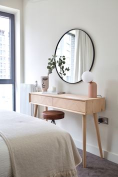 a bedroom with a bed, desk and mirror in it's corner area next to a window