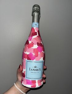 a hand holding a bottle of pink wine