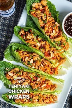 lettuce wraps filled with chicken and sauce on a white platter next to dipping sauce