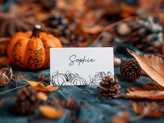 a table topped with lots of different types of pumpkins and pineconuts next to a card