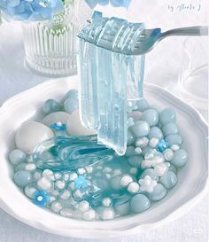 a toothbrush in a bowl filled with blue and white bubbles next to some flowers