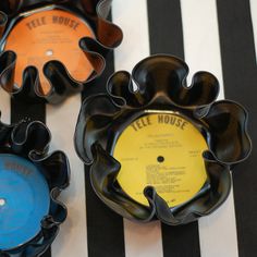 three black and white plates with various records on them sitting on a striped tablecloth