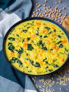 a bowl of yellow soup with spinach and carrots