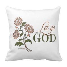 a white pillow with the words let go and let god printed on it, surrounded by daisies