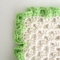 a crocheted dishcloth with green and white trim