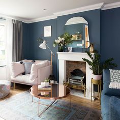 a living room filled with furniture and a fire place in front of a mirror on the wall