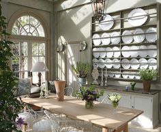 a dining room table surrounded by chairs and vases with flowers on the table in front of it