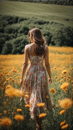 a woman standing in a field of flowers with her back to the camera looking down