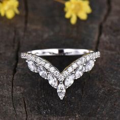 a close up of a diamond ring on a piece of wood with flowers in the background