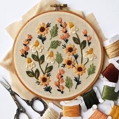 the embroidery is being worked on with scissors and thread, along with spools of thread