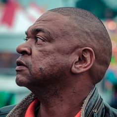 a close up of a person wearing a leather jacket and looking off into the distance