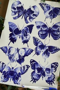 a sheet of paper with blue butterflies and skulls on it next to a plant filled with green leaves