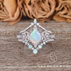 an opal and diamond ring sits on a wooden surface