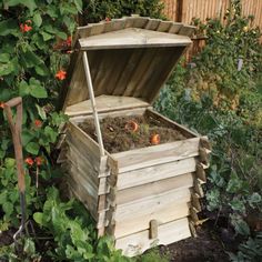 an old wooden box filled with dirt next to some plants and flowers in a garden