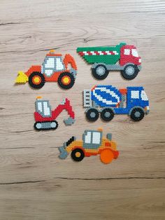 four pieces of plastic construction vehicles on a wooden surface with one piece cut out to look like it's made from legos