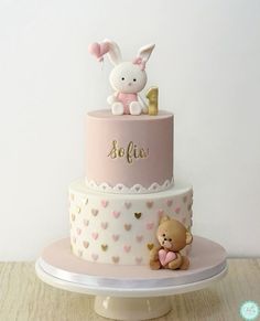 a pink and white cake with a teddy bear on top