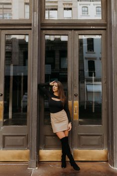 a woman standing in front of a door with her hand on her head and looking at the camera