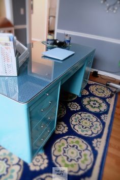 a blue desk with drawers on top of it and a rug in front of it