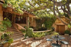 a patio with tables and chairs under a tree