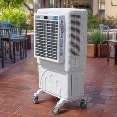 a white air conditioner sitting on top of a brick floor next to tables and chairs