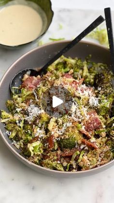 a bowl filled with broccoli and other food next to a container of dressing