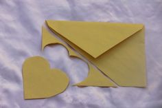 two pieces of yellow paper cut out to look like an envelope with a heart on it