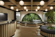 the inside of an office with plants on the wall and round tables in front of it