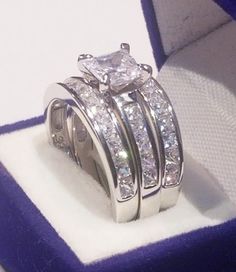 two wedding rings with princess cut diamonds in a box