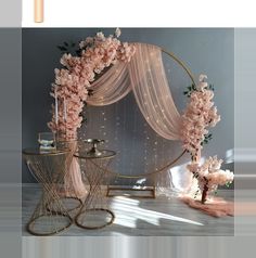 a table with flowers and candles on it next to a round metal stand that has sheer draping