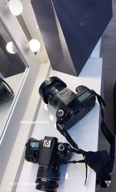 two cameras sitting on top of a counter next to a mirror