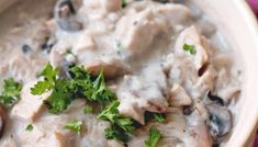 a close up of a bowl of food with mushrooms and parsley in the middle