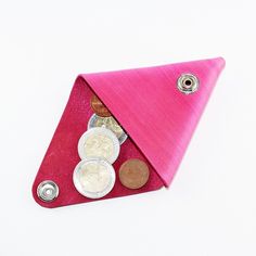 a pink triangle shaped purse with coins in it and a button on the front side