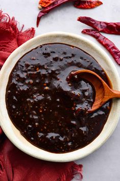 a white bowl filled with chili sauce next to red napkins and wooden utensils