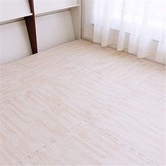 an empty bed room with a book shelf and white curtains on the window sill