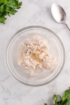 a bowl filled with oatmeal sitting on top of a table next to parsley