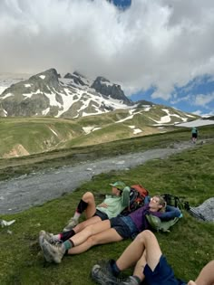 two people laying on the ground in front of a mountain