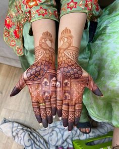 a woman's hands with henna tattoos on her arm and hand, showing the intricate design